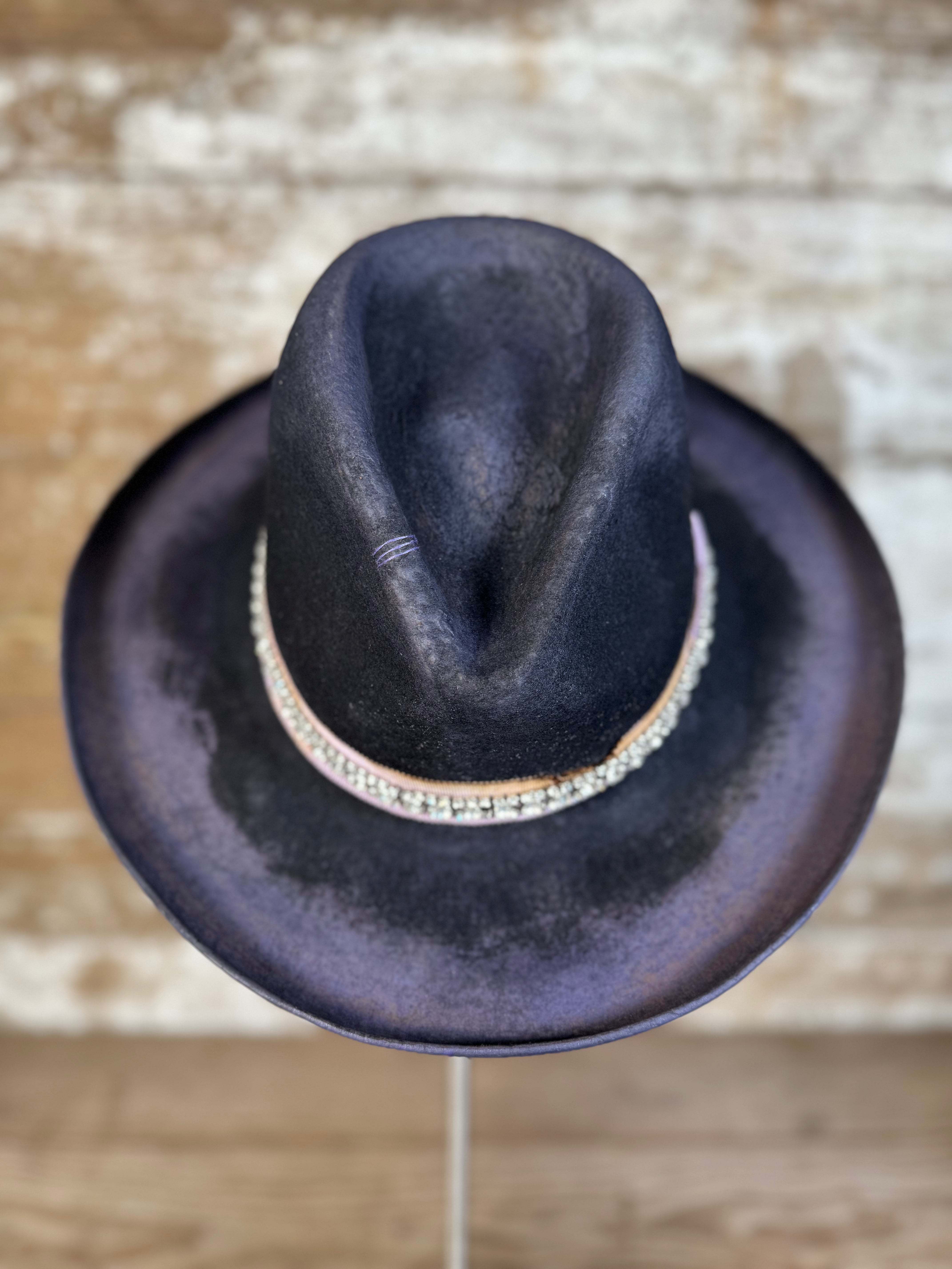 Front view of weathered violet-charcoal felt Gus hat with pencil curl brim, lilac petersham grosgrain ribbon, rhinestone band, hand stitching, and diamond brand mark.